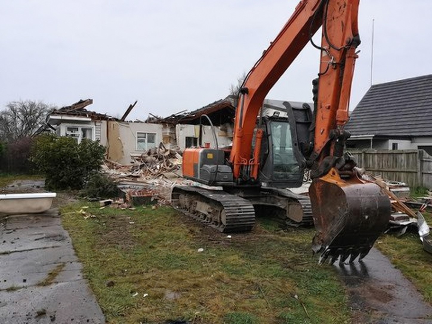 Next Earthworks + Construction Ltd excavator completing house demolition in Christchurch